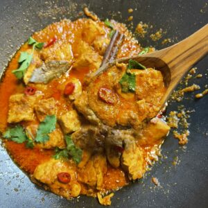 Curry met kip in een kruidige tomatensaus, geserveerd in de pan met verse koriander